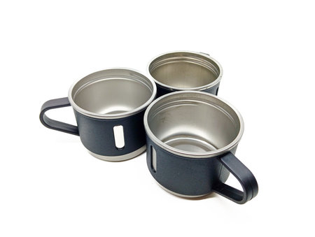 Top view of three empty stainless steel mugs with black handles arranged in a triangle on a white background, ideal for kitchenware or outdoor equipment visuals.の写真素材