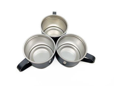 Top view of three empty stainless steel mugs with black handles arranged in a triangle on a white background, ideal for kitchenware or outdoor equipment visuals.の写真素材