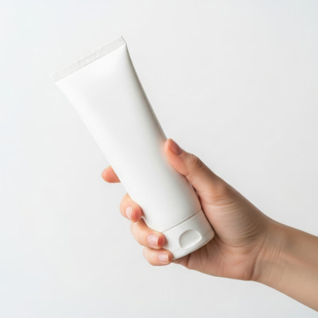 Hand holding a tube of cream against a plain backgroundの素材