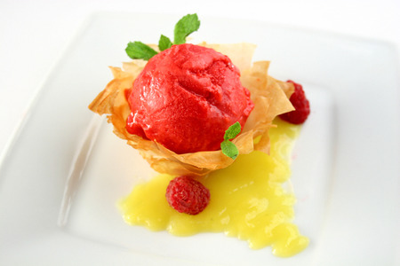 Delicious strawberry sorbet decorated with mint, raspberries and cream on the baked basketの写真素材
