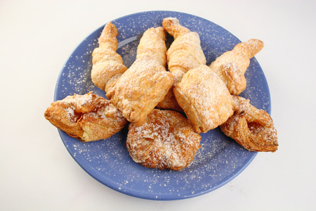 Fresh buns with powdered sugar on blue plateの写真素材