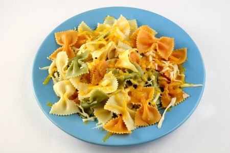 Coloured farfalle with cheese on blue plateの写真素材