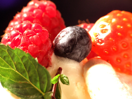 Fresh paspberries, blueberries and strawberries in vanilla cream with mintの写真素材