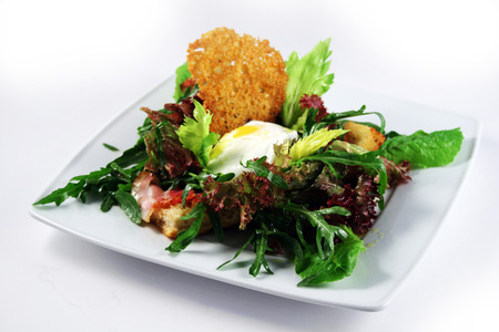 Green salad with poached egg, bread crisp, olive oil and fried baconの写真素材