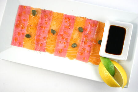 Delicious carpaccio from salmon and tuna with capers, red caviar, lemon and soy sauceの写真素材