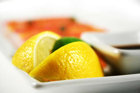 Two wedges of lemon with a slice of lime and soy sauseの写真素材