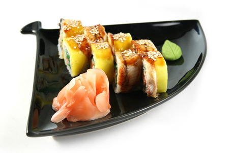 Asian food sushi roll with eel, crab, chuka, avocado and sesam on black plateの写真素材