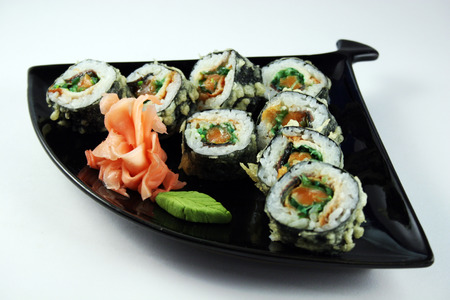 Delicious sushi roll with salmon and chuka on black plateの写真素材