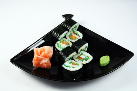 Delicious sushi roll with salmon and chuka on black plateの写真素材