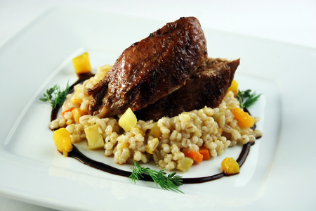 Delicious fried pork with barley groats, pepper and wine sauceの写真素材