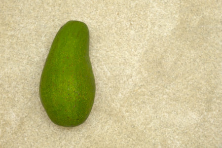 Unripe Avocado on brown background. Name latin is Persea americana. Alpukat