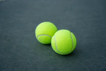 Two yellow tennis balls on the green background. Close up.