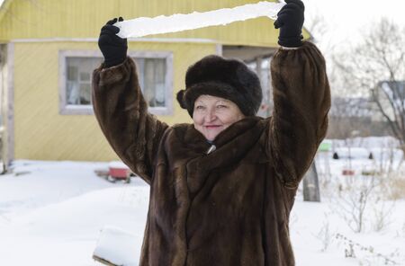 Woman in the winter in the country holds over his head icicle ice.の写真素材
