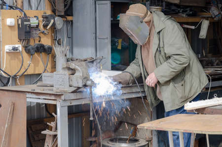 Man welds welding iron parts in the garage.の写真素材