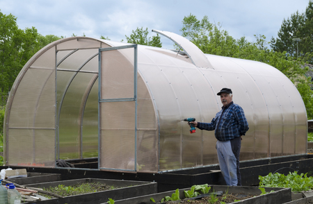 The man in the country screwdriver fastens to the polycarbonate greenhouse.の写真素材