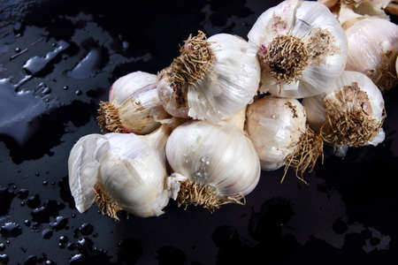Fresh garlics on a  wet dark backgroundの写真素材
