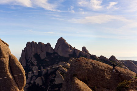 Man practicing highline in Montserrat, Spain. Highline is an equilibrium sport which consists on walking through a rope clamped between two points.の写真素材