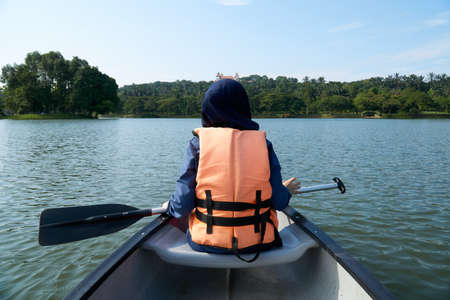 Unidentified Muslim women wearing safety jacket kayaking at the lakeの写真素材