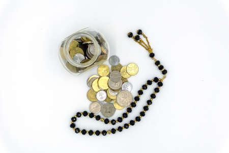 Top view of coins and rosary over white backgroundの写真素材