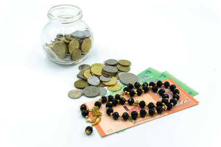 Top view of Coins, Malaysia Ringgit bank notes and rosary over white backgroundの写真素材