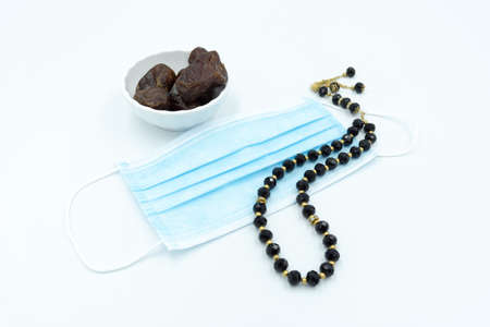 Dates in white cup with face mask and black prayer beadsの写真素材