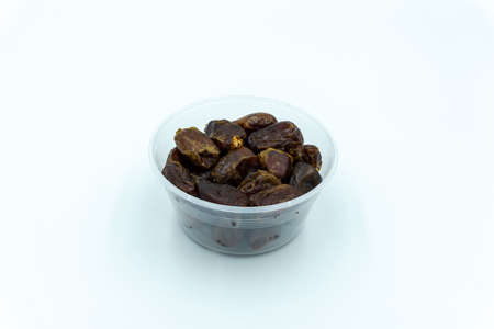 Dates in a large plastic container over white backgroundの写真素材