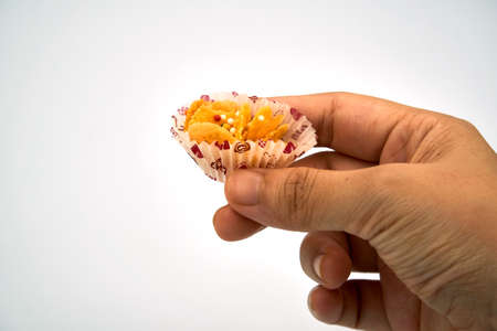 Hand holding single honey cornflakes over white backgroundの写真素材