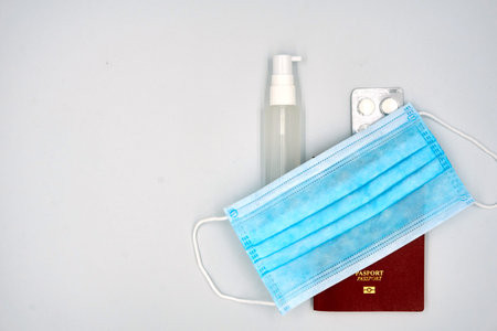 Small sanitizer, pills medicine, and passport over white background
