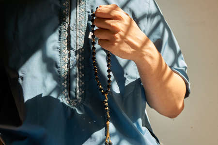 Muslim man holding black colored prayer beads during prayerの写真素材