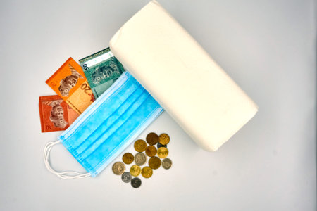 Malaysia Ringgit coins and notes, blue surgical face mask and roll tissue over white background