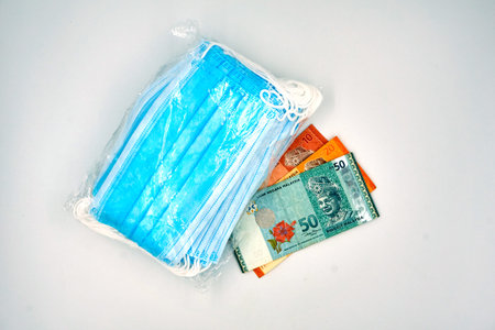 Surgical face mask in the plastics with Malaysia Ringgit notes over white background