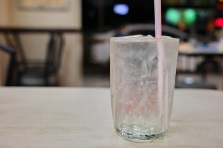 Selective focus of glass of iced water with straw at restaurantの写真素材