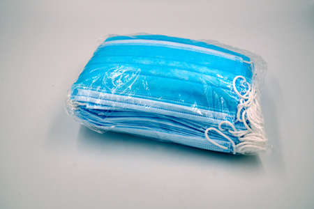 Bundle of blue surgical face mask in a plastic over white backgroundの写真素材