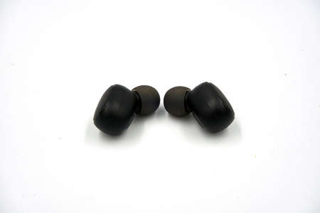 Pair of black wireless earbud or earphone over white backgroundの写真素材
