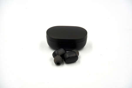 Black colored wireless earbud with black colored charging case over white backgroundの写真素材