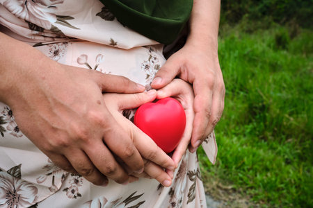 Selective focus of pregnant women holding hand with husband and love symbol toy on the stomach