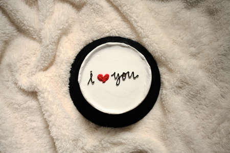 White colored cake with I love you written on top over white clothの写真素材