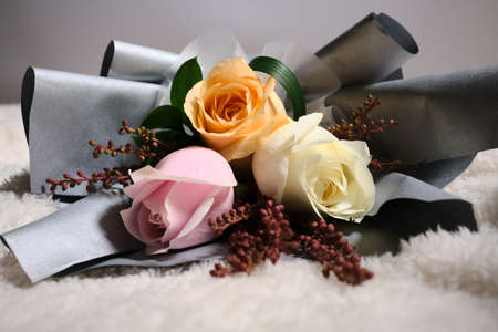 Selective focus of white, yellow and pink roses over white clothの写真素材