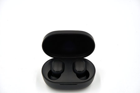 Pair of wireless earbuds in the charging case over white background