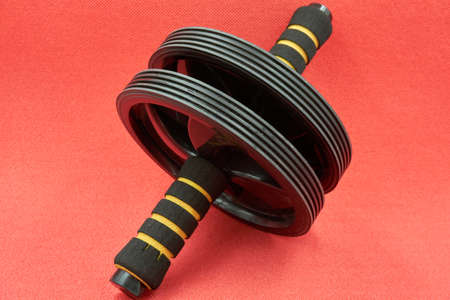 Black colored abs roller on the red colored yoga matの写真素材