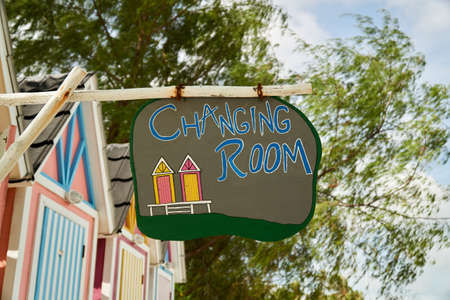 Small colorful hanging wooden changing rooms signage by the beachの写真素材