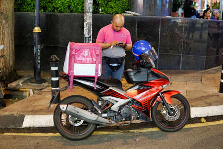 Foodpanda delivery man checking his phone for order during the nightのeditorial素材