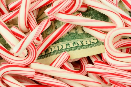 Illustrating the high cost of the Christmas holidays, money lies on a bed of candy canes.の写真素材