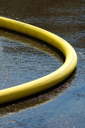 Fire department supply and attack hose on wet asphalt pavement の写真素材