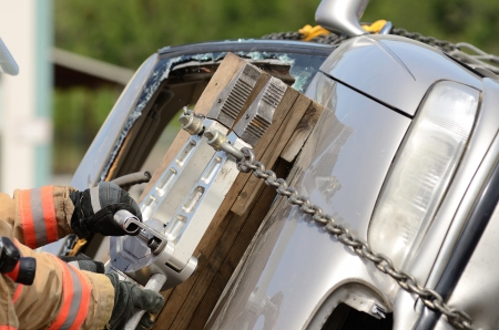 Firefighters working on an auto vehicle extrication with a hydraulic power rescue toolの写真素材