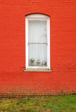 oil lamps in a old white framed window against a painted red brick wall in Historic Oakland Oregon   This building is the old oakland hotel の写真素材