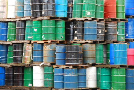 A large stack of old chemical barrels sit at and industrial plant