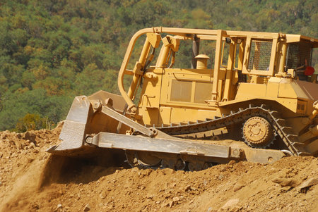Large tracked bulldozer moving rock and dirt from a hill for a new commercial development
