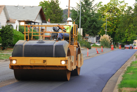 Large vibrating roller compactor working on an asphalt repaving project in Roseburg Oregon