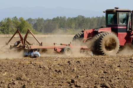 Farmer using a disc cultivator to break of soil after plowing on a field in Oregon の写真素材